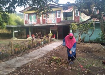 NORHASIYATI Taharin sedang membersihkan kawasan landskap Tahan Guest House miliknya yang belum lagi disinggahi pengunjung di Kuala Tahan di Jerantut, Pahang.