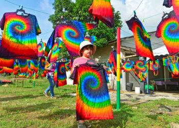 WAEL Anaqi Efendy, 5, cucu kepada pengusaha Umi-TieDye membantu mengangkat baju yang telah kering di Cherating, Pahang. - FOTO/SHAIKH AHMAD RAZIF
