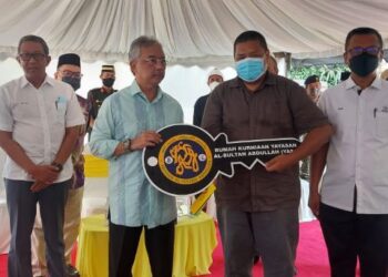 Al-SULTAN ABDULLAH Ri'ayatuddin Al-Mustafa Billah Shah (tiga dari kanan) menyampaikan replika kunci rumah kurniaan YASA kepada Shaharim Ahamad Amiruddin di Kampung Tanjung Putus, Dong di Raub, Pahang. - FOTO/SALEHUDIN MAT RASAD