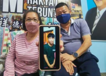 LOKE Chooi Tip (kiri) menunjukkan gambar anaknya di dalam telefon bimbitnya yang didakwa ditipu sindiket penipuan pekerjaan sehingga dibawa ke Myanmar - FOTO/DIANA SURYA ABD. WAHAB