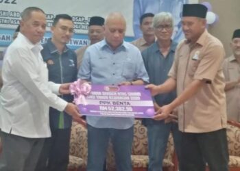MOHD. Soffi Abdul Razak (tengah) menyampaikan replika cek dividen keuntungan kepada Mohd. Razaki Abd. Razak (kanan) di pekan Benta di Lipis, Pahang. - FOTO/HARIS FADILAH AHMAD