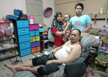 FAZZIAH Abdullah (berdiri kiri) mendukung anak keempatnya bersama Akbar Nizam Hamzah (berbaring) dan seorang anak lelaki berusia 15 tahun di rumah ibu bapa mereka di Felda Kota Gelanggi Dua di Jerantut, Pahang. - UTUSAN/HARIS FADILAH AHMAD