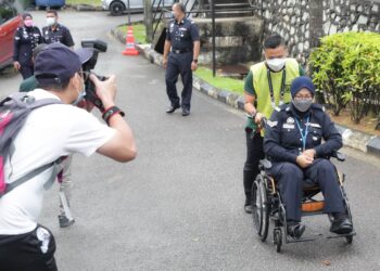 PETUGAS SPR, Mohd. Mustaqim Naser membawa Koperal Siti Maslinda Nordin hadir pada proses pengundian awal di Dewan Serbaguna IPK Melaka, Bukit Beruang, Melaka. - UTUSAN/RASUL AZLI SAMAD