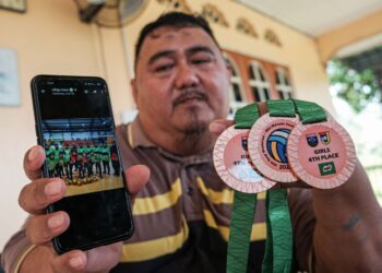ABD. HALIM Bakar menunjukkan pingat kejohanan berserta gambar anaknya ketika ditemui di rumahnya di Melekek, Alor Gajah, Melaka. - UTUSAN/SYAFEEQ AHMAD