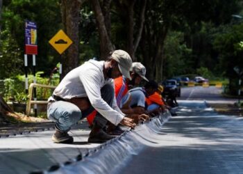 KERJA-KERJA pemasangan kanvas bagi mengurangkan risiko runtuhan tanah giat dilakukan di Jalan Bukit Permai 1. - UTUSAN/SHIDDIEQIIN ZON