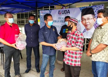 JALALUDDIN Alias (tiga, kiri) menyampaikan sumbangan daging korban kepada salah seorang penerima pada Program Korban Perdana UDA 2020 di Seremban, semalam. – UTUSAN/NOR SHAFAWATI YUP