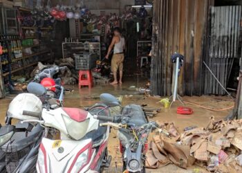 Seorang pemilik kedai membaiki motosikal di Batu 14, Hulu Langat, Selangor,  membersihkan kedainya yang dimasuki air kelmarin.