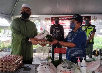RAZMAN Zakaria (kanan) menyerahkan sumbangan untuk penduduk terlibat PKPD kepada Mohd. Sabli Bakri di Bukit Merah, Bagan Serai hari ini. - UTUSAN/WAT KAMAL ABAS