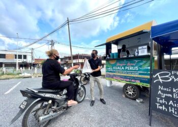 SYAMIL ABD. RAHMAN memberikan nasi kukus ayam berempah kepada pelanggan yang datang ke kiosk Samudera Coffee House di  tapak meletak kereta Pasar Raya Seri Utama Kuala Perlis, semalam. - MINGGUAN/NAZLINA NADZARI