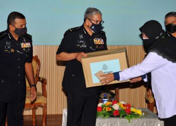 MAZLAN Lazim menyampaikan sumbangan kepada salah seorang pesara polis wanita sambil diperhatikan Ayob Khan Mydin Pitchay (kiri) pada Majlis Sumbangan Kepada Pesara Polis di Dewan Auditorium IPK Johor di Johor Bahru. -UTUSAN/RAJA JAAFAR ALI