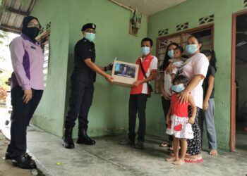 RAKESH Chiafongsin sekeluarga menerima kit makanan yang disampaikan oleh Ketua Bahagian Pencegahan Jenayah dan Keselamatan Komuniti Daerah Jasin, Asisten Superintenden Meran Anak Emai di Lubok Bandung, Melaka. - UTUSAN/DIYANATUL ATIQAH ZAKARYA