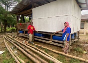 ROSLAN Hassan dan  isterinya, Erawati Jaafar menunjukkan pondok terapung yang dibina 
di Kampung Teladas, Air Putih, Kemaman, Terengganu. - UTUSAN/NIK NUR IZZATUL HAZWANI NIK ADNAN