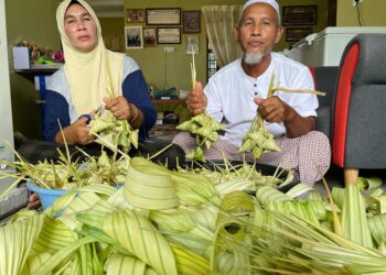 MAT Wani Jusoh dan Norma Adam membuat ketupat untuk empat anak mereka yang tidak dapat pulang menyambut Hari Raya Aidiladha bersama. - UTUSAN/TOREK SULONG