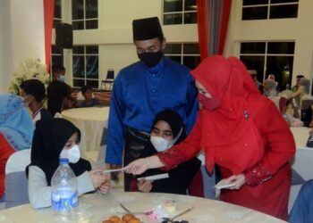 NORLIZA Abdul Rahim sambil diiringi Mohd. Salem Kailany menghulurkan duit raya kepada anak yatim dan asnaf dalam majlis berbuka puasa di Rumah Kelab Crescent Dew, Bertam, Kepala Batas, Pulau Pinang, semalam.