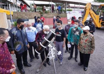 AHMAD FUZI Abdul Razak (tengah) mencuba teleskop yang dipamerkan pada majlis pecah tanah untuk projek pusat pemerhatian astronomi di sekolah tersebut di Bukit Mertajam, Pulau Pinang, hari ini.