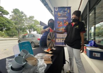 TRACY Loh (kiri) melayani pelanggan yang mencuba permainan putaran bertuah di hadapan JMS Freshmart, Bukit Mertajam, Pulau Pinang, semalam. – FOTO/SITI NUR MAS ERAH AMRAN
