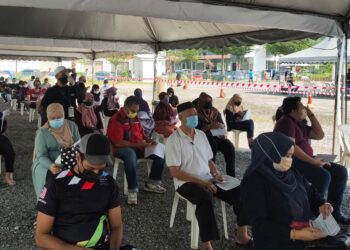 SEBAHAGIAN penduduk menunggu giliran sebelum menerima vaksin Covid-19 mereka di Nilai Impian, Nilai, Seremban, kelmarin. - UTUSAN/AFIFI HAFIZ MOHD. NOR