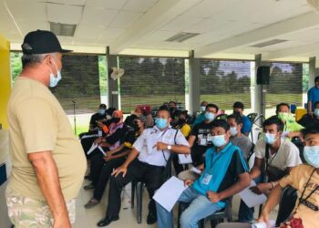 NAZRI Ngah (berdiri, kiri) beramah mesra dengan penduduk yang menunggu suntikan vaksin di Dewan Sekolah Kebangsaan Hulu Tembeling, Jerantut. - HARIS FADILAH AHMAD