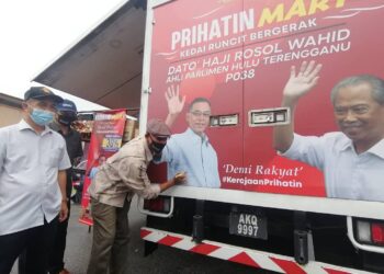ROSOL Wahid (kanan) menurunkan tandatangan pada bahagian belakang kedai runcit bergerak, Prihatin Mart di Dataran Padang Kacung, Kuala Telemong, Hulu Terengganu hari ini.