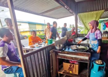 NURUL Asyikin Noorazizi menyediakan roti canai untuk pelanggan di warung keluarganya di Kampung Sungai Tiang Darat, Bagan Datuk, Perak. - UTUSAN/AIN SAFRE BIDIN
