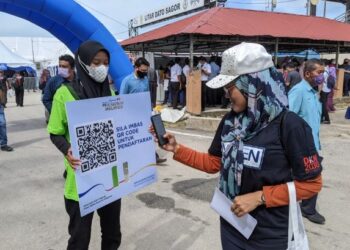 SEORANG pengunjung mengimbas kod pendaftaran Karnival JAKM Negeri Perak di Litar Dato' Sagor, Kampung Gajah di Pasir Salak, Perak, hari ini.- FOTO/MOHAMAD HAFIZI MOHD. SAID