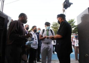 MIOR  Faridalathrash Wahid (kanan) memberikan pelitup muka kepada pelajar tingkatan enam SMK St. Michael, S. Sivanathan (tengah) ketika program Pemantauan Pematuhan  SOP PPN Fasa Dua di sekolah itu di Ipoh, semalam. - UTUSAN
