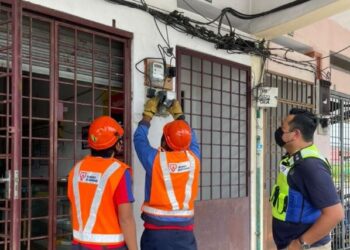 PEKERJA TNB melakukan kerja pemotongan bekalan elektrik di premis yang diserbu kerana menjalankan kegiatan judi dalam talian di Gopeng, Perak, semalam. - FOTO/IHSAN PDRM PERAK