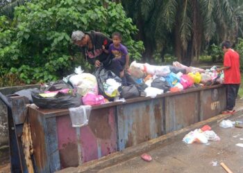 JASMIN Bakaruddin bersama anak-anaknya mencari barangan terpakai di tempat pembuangan sampah di Kampung Bahagian Teluk Intan, Perak. - UTUSAN/AIN SAFRE BIDIN