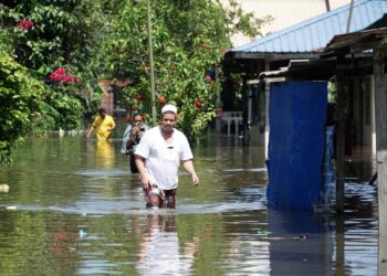 PENDUDUK meredah banjir setelah kediaman mereka dinaiki air di Kampung Batu 7 1/2, Lorong Mesra Jalan Changkat Jong, Teluk Intan, Perak, semalam. - UTUSAN/ZULFACHRI ZULKIFLI