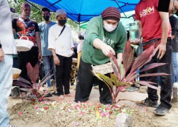 MOHD. Khalid Amen Mohamad menabur bunga mawar di kubur Allahyarham Mamat Khalid sambil diperhatikan Bell Ngasri (baju putih) di Tanah Perkuburan Islam Masjid Kampong Paloh, Ipoh, Perak, semalam. - UTUSAN/ZULFACHRI ZULKIFLI