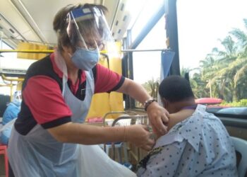 HEE Kim Lan menyuntik seorang penerima vaksin pada Program Movac di Japerun Machap Jaya, Alor Gajah, Melaka. - UTUSAN/MUHAMMAD SHAHIZAM TAZALI