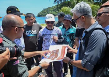 TUN Ahmad Faizal Tun Abdul Razak (tengah) diberi taklimat pembangunan daripada pegawai Taman Negeri Terengganu di Pulau Bidong, Kuala Nerus, hari ini. - UTUSAN/PUQTRA HAIRRY ROSLI