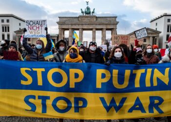 PESERTA demonstrasi memegang sepanduk tertera 'Stop Putin, Stop War' dalam warna bendera Ukraine di Pintu Brandenburg, Berlin.-AFP