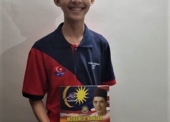 PENULIS memegang buku Mohamed Hamzah Pereka Cipta Jalur Gemilang.