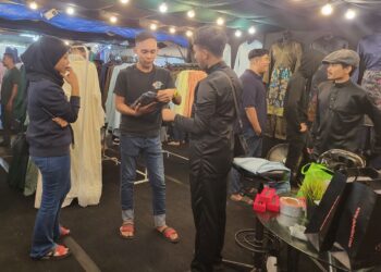 MOHD. REDZA FAHMI Faiza (tengah) sedang melayan pelanggan di gerai jualan baju Melayu, kurta dan jubah miliknya di Dataran Sekilau di Kuantan, Pahang.