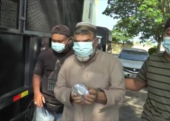 MOHD. Ridi yang dituduh cuba meraba dan memegang tangan seorang jururawat diiringi anggota polis di Mahkamah Majistret di Butterworth, Pulau Pinang hari ini.