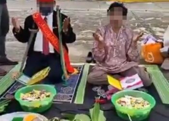 IBRAHIM Mat Zin (kiri) bersama seorang wanita dikenali Puteri Zaleha melakukan upacara menolak musibah banjir di Dataran JPS, Teluk Intan yang tular dalam media sosial. - FOTO MEDIA SOSIAL