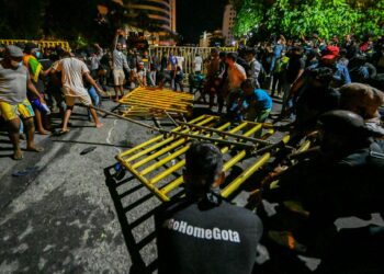 PENUNJUK perasaan merobohkan pagar halangan yang dipasang polis dalam protes di Colombo pada 28 Mei lalu. - AFP