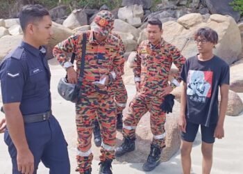 FADHLI Simon (kanan) ketika ditemui anggota bomba di Pantai Teluk Chempedak di Kuantan, Pahang. - FOTO IHSAN JBPM PAHANG
