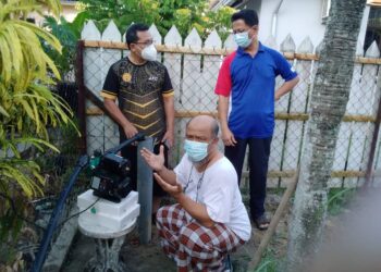 ARIFFIN Awang (duduk) bersama jiran menunjukkan telaga tiub dibina di kawasan rumah mereka di Taman Harian, Kota Bharu kerana sering berdepan gangguan bekalan air sejak menetap di situ lebih 20 tahun lalu. - UTUSAN/ROHANA MOHD. NAWI
