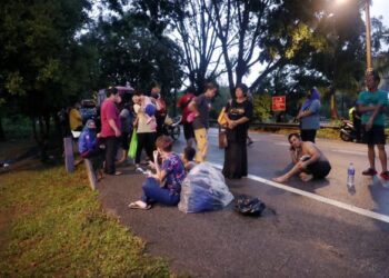 PENDUDUK beralih di kawasan selamat ketika kawasan perumahan mereka ditenggelami air selepas hujan lebat di Solok Benteng, Kampung Sungai Putat, Melaka. - FOTO/RASUL AZLI SAMAD