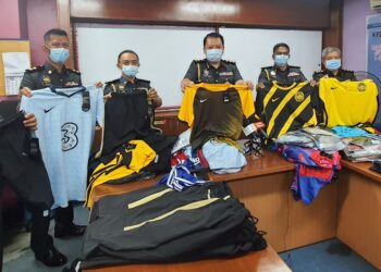 MOHD. Shahran Mohd. Arshad (tengah) bersama anggota penguatkuasa KPDNHEP Cawangan Kubang Pasu menunjukkan pakaian sukan berjenama  disyaki tiruan yang dirampas di kawasan perindustrian Bandar Darulaman, Kedah, semalam.