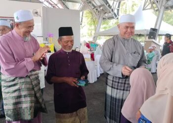 RAZMAN Zakaria (kanan) menyampaikan duit raya kepada kanak-kanak pada Majlis Rumah Terbuka Aidilfitri Pas Perak di Dataran Amanjaya, Lawin di Lenggong hari ini. - UTUSAN/WAT KAMAL ABAS