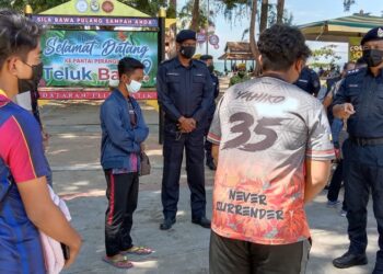 NOR Omar Sappi (kanan) memberi nasihat kepada sekumpulan remaja bermotosikal dengan ada antara mereka tiada sijil vaksinasi lengkap dalam operasi pematuhan di Teluk Batik, Lumut, Perak, hari ini. - UTUSAN/SHAMSUL KAMAL AMARUDIN