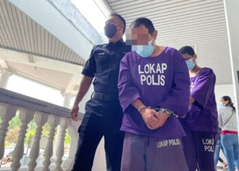 SUSPEK yang menikam leher ibu kandungnya sehingga maut diiring keluar anggota polis selepas dihadapkan ke Mahkamah Majistret Ayer Keroh, Melaka. - UTUSAN/MUHAMMAD SHAHIZAM TAZALI