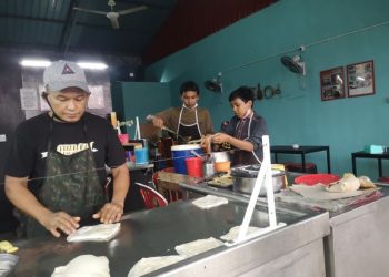 RENGGO dibantu dua anaknya ketika berniaga roti canai di Kampung Sungai Petai, Pasir Puteh, Kelantan semalam. – FOTO/TOREK SULONG