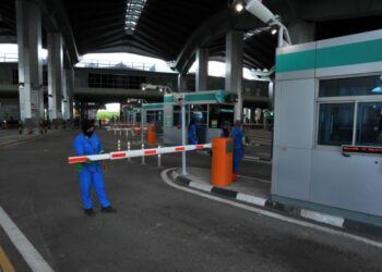 Beberapa pekerja membersihkan kawasan di laluan masuk kenderaan dari Singapura sebagai persiapan pembukaan sempadan antara kedua-dua buah negara bermula esok di Kompleks Sultan Abu Bakar, Laluan Kedua di Iskandar Puteri dekat Johor Bahru, semalam. – UTUSAN/RAJA JAAFAR ALI.