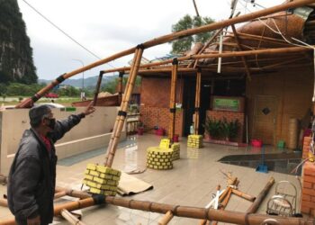 SEORANG petugas menunjukkan bumbung Masjid Buluh yang tercabut dipukul ribut petang semalam. - UTUSAN/AIMUNI TUAN LAH