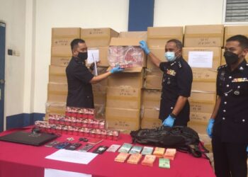 MOHAMAD Noor Yusof Ali  (tengah) menunjukkan rokok seludup yang dirampas Jumaat lalu, dalam satu serbuan di Gambang di Kuantan di Stor Barang Kes Berpusat PDRM di Kuantan, Pahang. FOTO/DIANA SURYA ABD. WAHAB