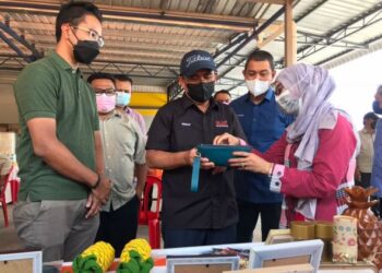 RONALD Kiandee (tengah) melihat kraftangan menggunakan daun nanas di salah sebuah pameran di Kilang Pau Mira Frozen, Pagoh, Muar, Johor. - FOTO/NUR ALINA HASSAN